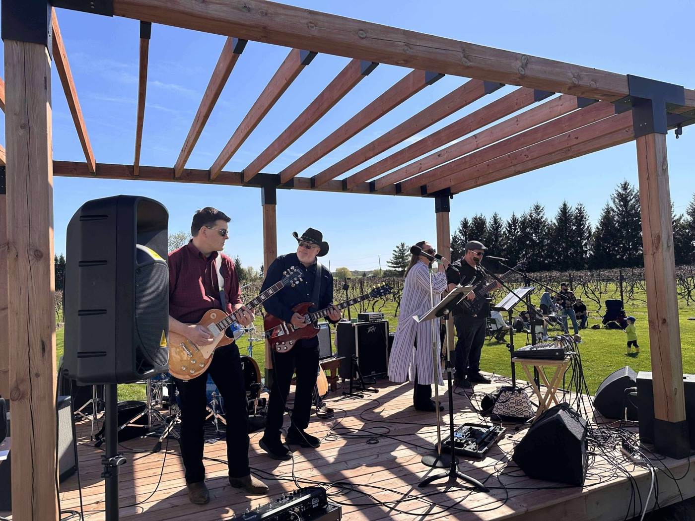 Retrospect mid-song at VKH Vineyard, vineyard rows visible behind the stage