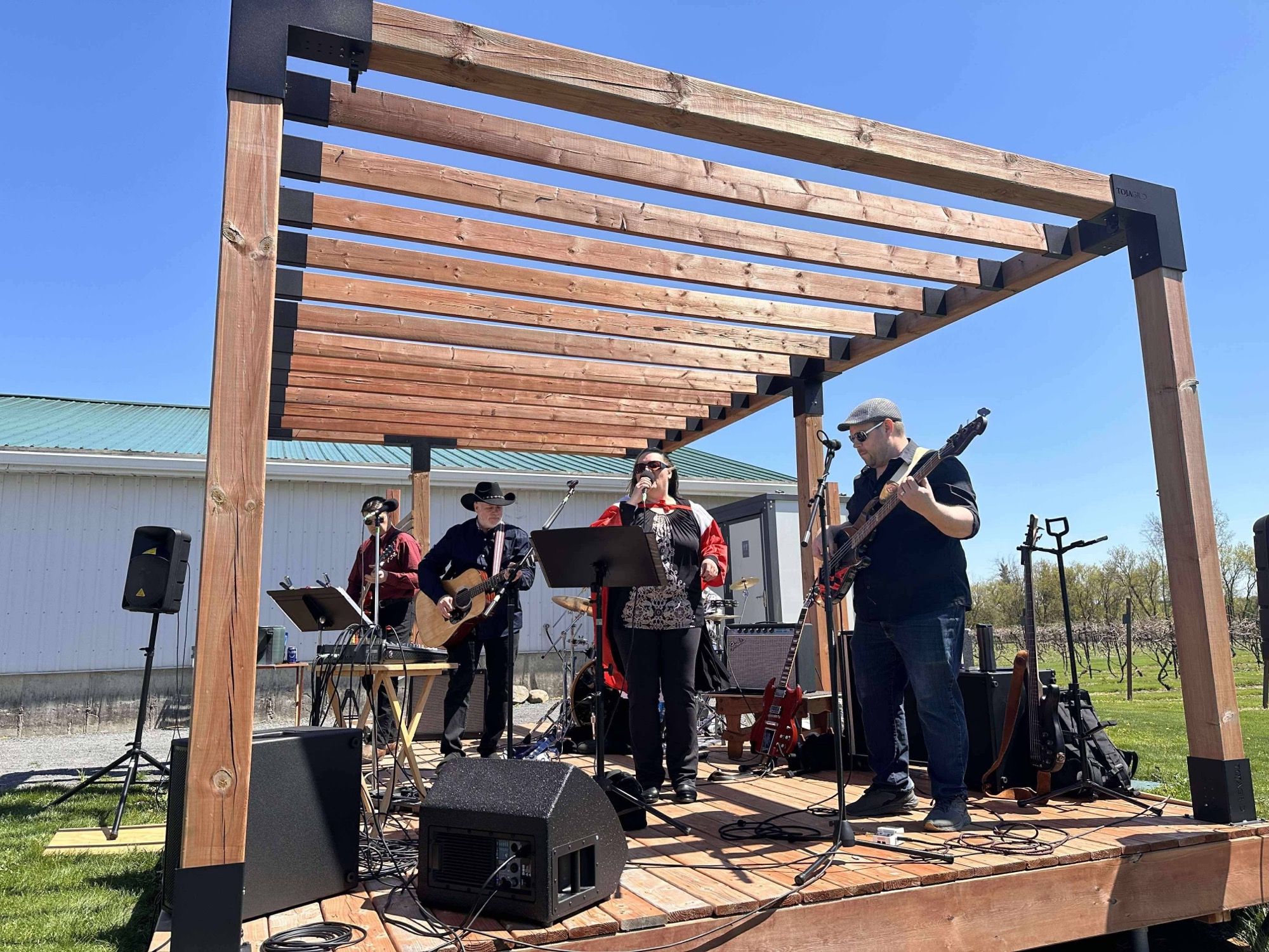Retrospect performing under the pergola stage at VKH Vineyard, summer 2025